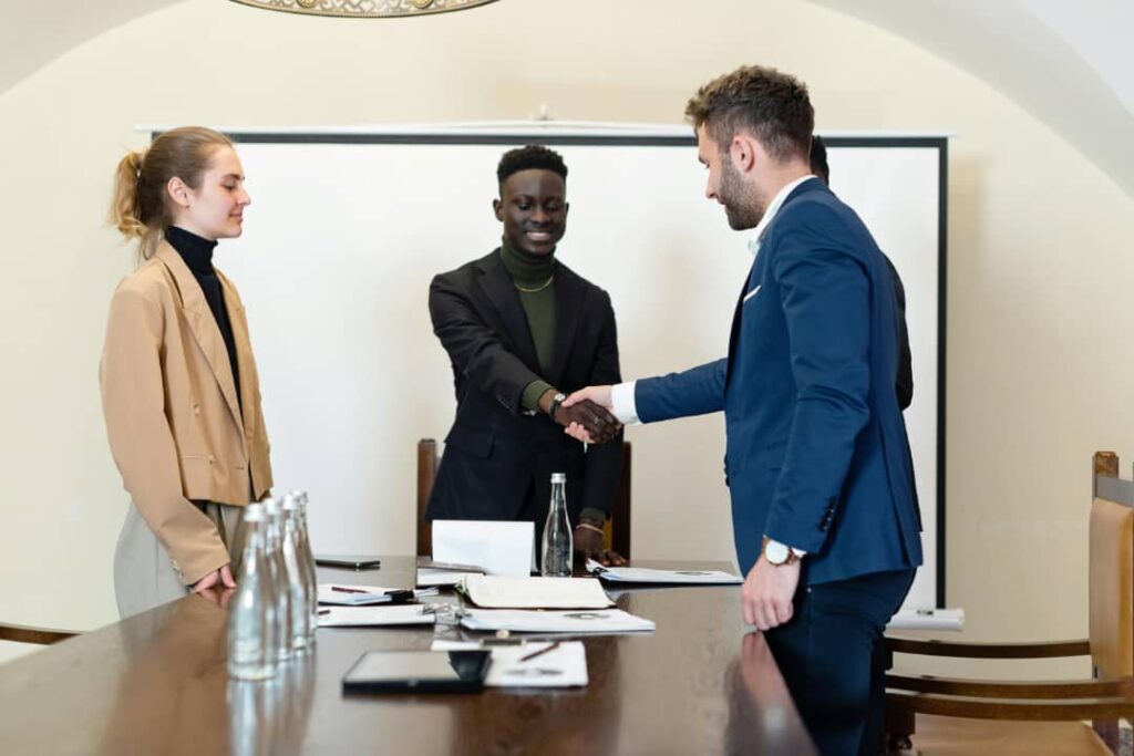 A group of people standing around a table shaking hands.