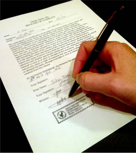 A person is signing papers with a pen.