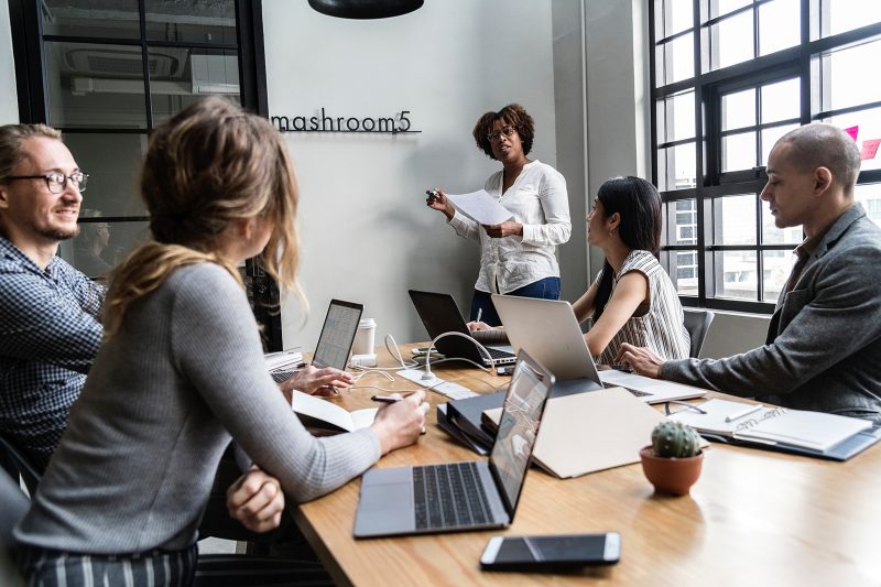 A group of people sitting at a table with laptops.